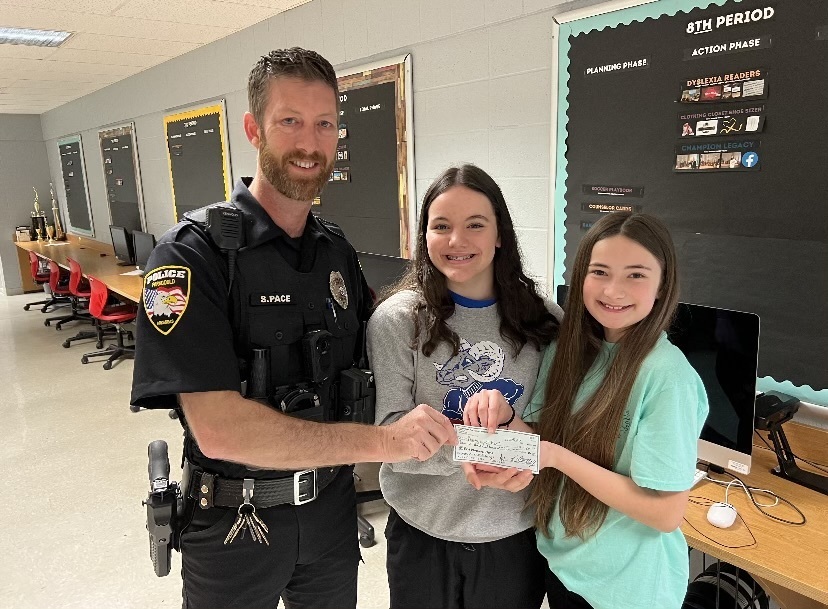 SRO delivering check to OGMS EAST students
